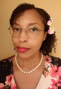 Image of Shykia Bell in a floral dress, pearls, glasses and a flower in her hair